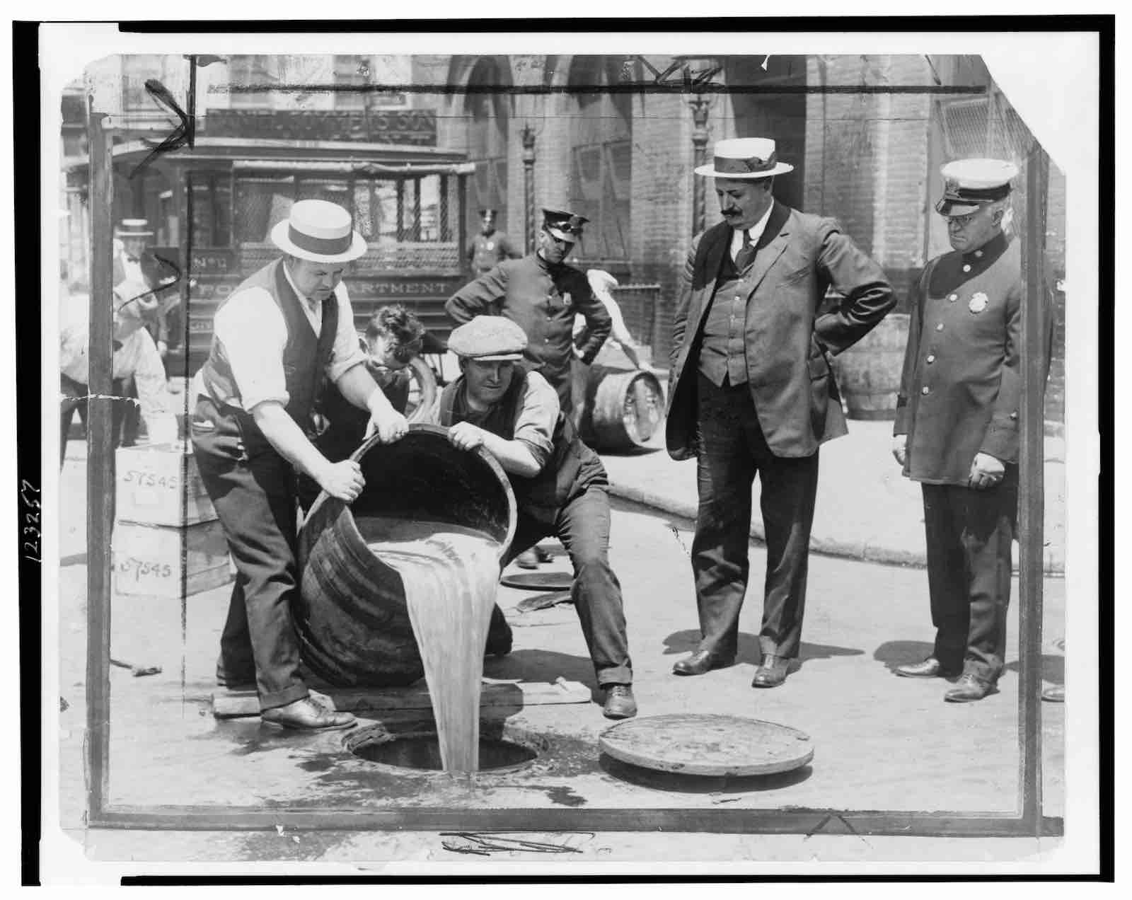 New York City Deputy Police Commissioner John A. Leach watching agents pour liquor into sewer, ca. 1921. Unknown photographer.