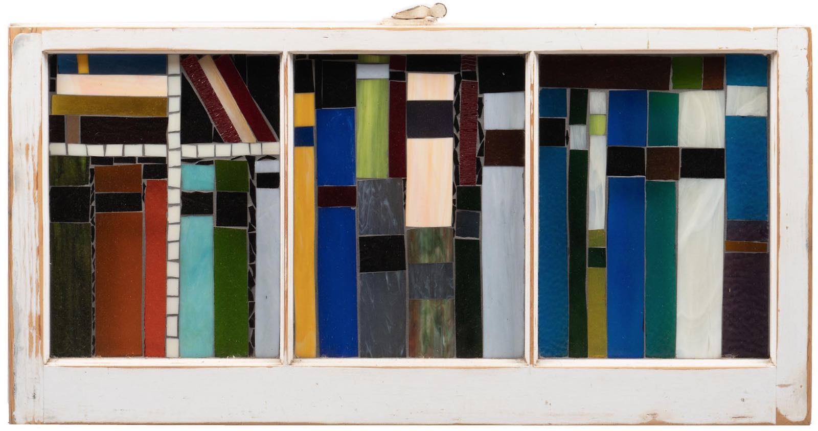 A stained glass window in decorative bookshelf motif, leaded, in painted window frame